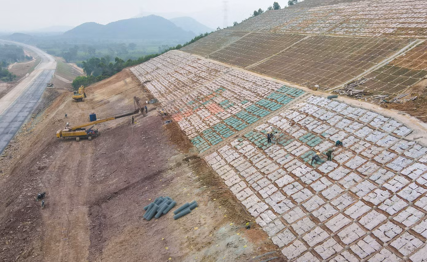 Ngọn đồi cao hàng chục mét qua xã Cẩm Thịnh (huyện Cẩm Xuyên) đã được đơn vị thực hiện dự án hạ độ cao, hoàn thiện mặt đường và đang cho công nhân gia cố ta luy.