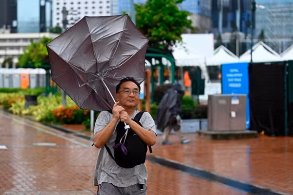 Một người dân ở Hong Kong (Trung Quốc) bị gió thổi lật chiếc ô khi bão Koinu (nước ta gọi là bão số 4) sắp đến. Ảnh chụp tháng 10/2023. Ảnh: AFP.