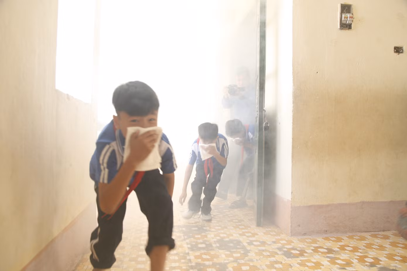 Công an hướng dẫn các em học sinh thoát khỏi đám cháy có nhiều khói. Ảnh: Nguyễn Thắng