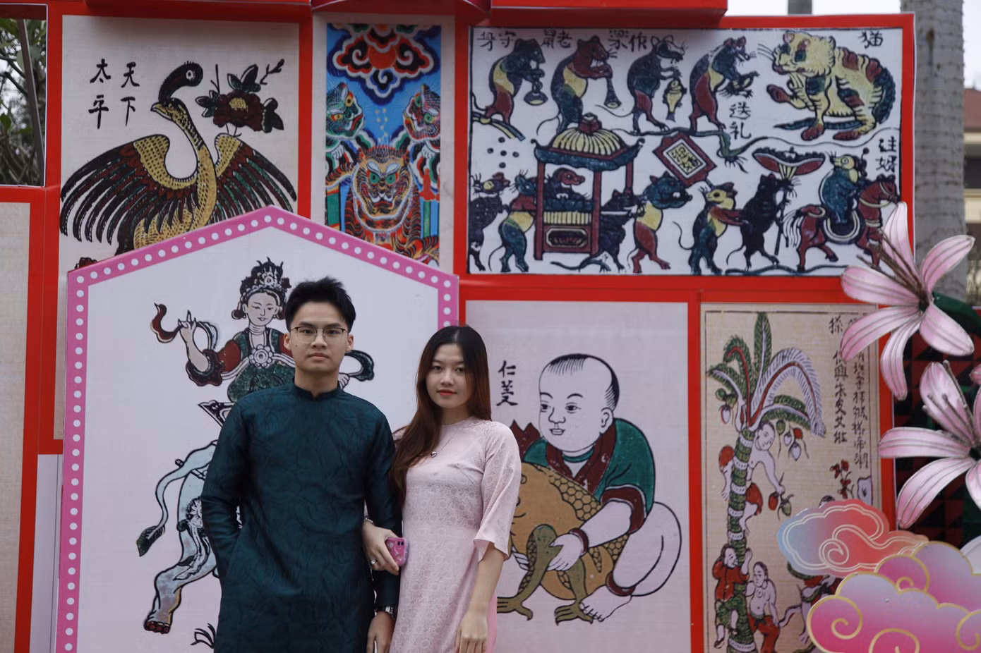 Đường hoa Tết ở thành phố Bắc Ninh có hơn 20 tiểu cảnh, mô hình trang trí tái hiện văn hóa Kinh Bắc được thiết kế bằng chất liệu chính là mây tre đan truyền thống và lấy cảm hứng từ nón quai thao, dải lụa đào. Các bạn trẻ chụp ảnh với mô hình tranh Đông Hồ. Ảnh: Nguyễn Thắng