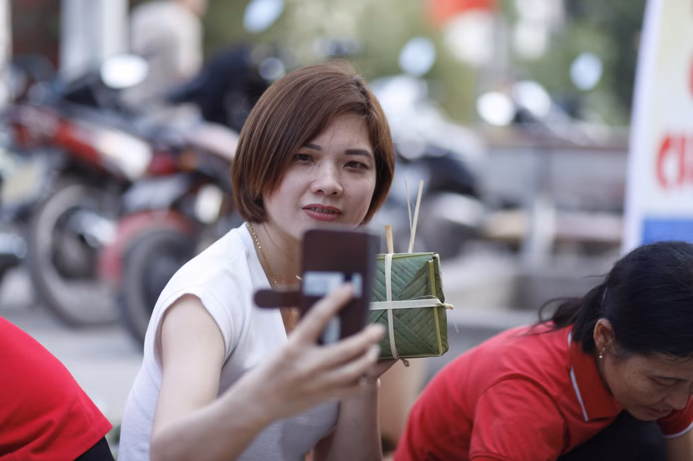Một công nhân xa quê vui vẻ chụp ảnh kỷ niệm chiếc bánh chưng tự tay gói. Ảnh: Nguyễn Thắng