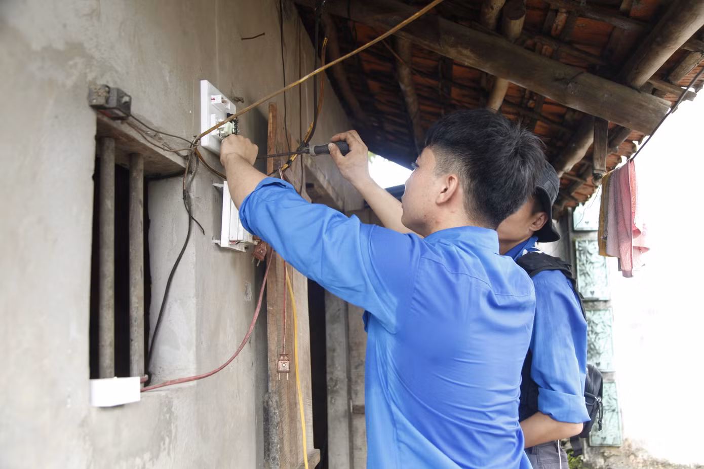 Sinh viên tình nguyện sửa điện giúp gia đình thương binh. Ảnh: Nguyễn Thắng