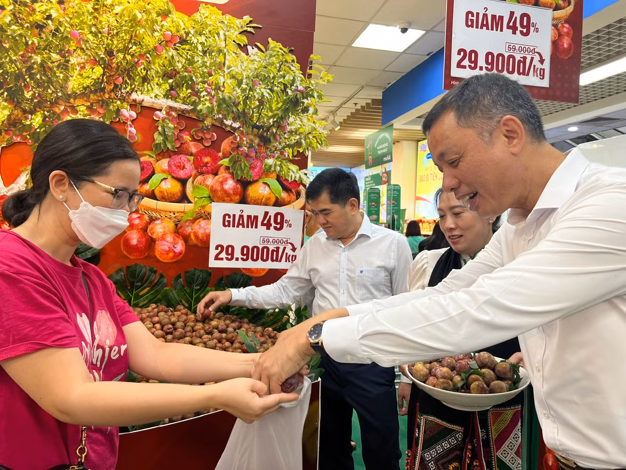 Ông Nguyễn Thành Công (bìa phải), Phó Chủ tịch UBND tỉnh Sơn La tặng mận hậu miễn phí cho khách hàng