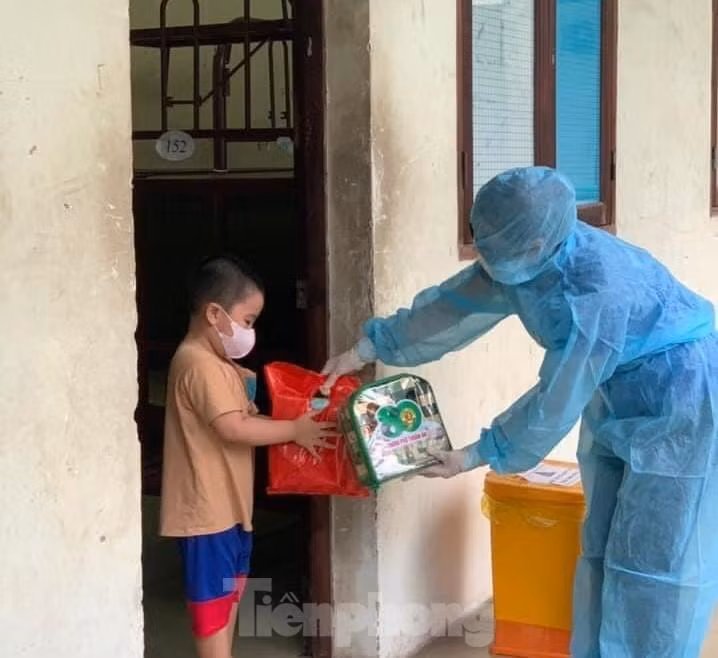 Tình nguyện viên tặng quà cho bé trai trong khu cách ly