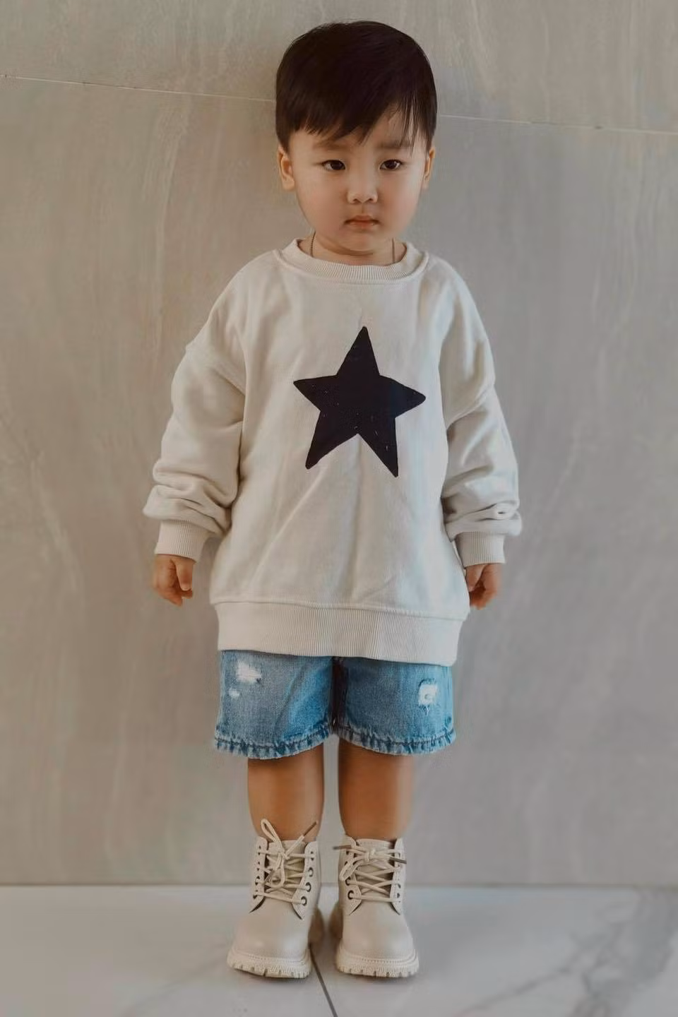 Quần jeans kết hợp với áo sweater là một lựa chọn yêu thích của Hòa Minzy cho con trai.