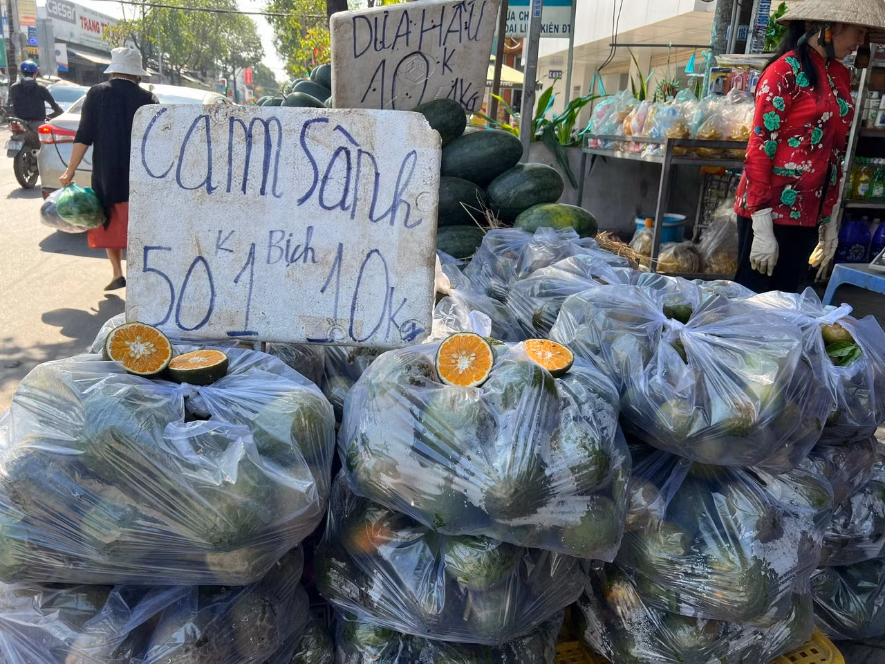 Trưa ngày 7/11, trên đường Phạm Hùng (huyện Bình Chánh, TPHCM), tiểu thương bày hàng chục bịch cam sành ngay trên vỉa hè, mở loa oang oang chào mời khách mua cam với giá 50.000 đồng/bịch 10kg. "Cam sành ở miền Tây đang vào mùa nên già trái, ngọt nước, em mua về uống tăng cường vitamin C giúp giải nhiệt nắng nóng, rất tốt cho sức khỏe" - người bán mời khách.