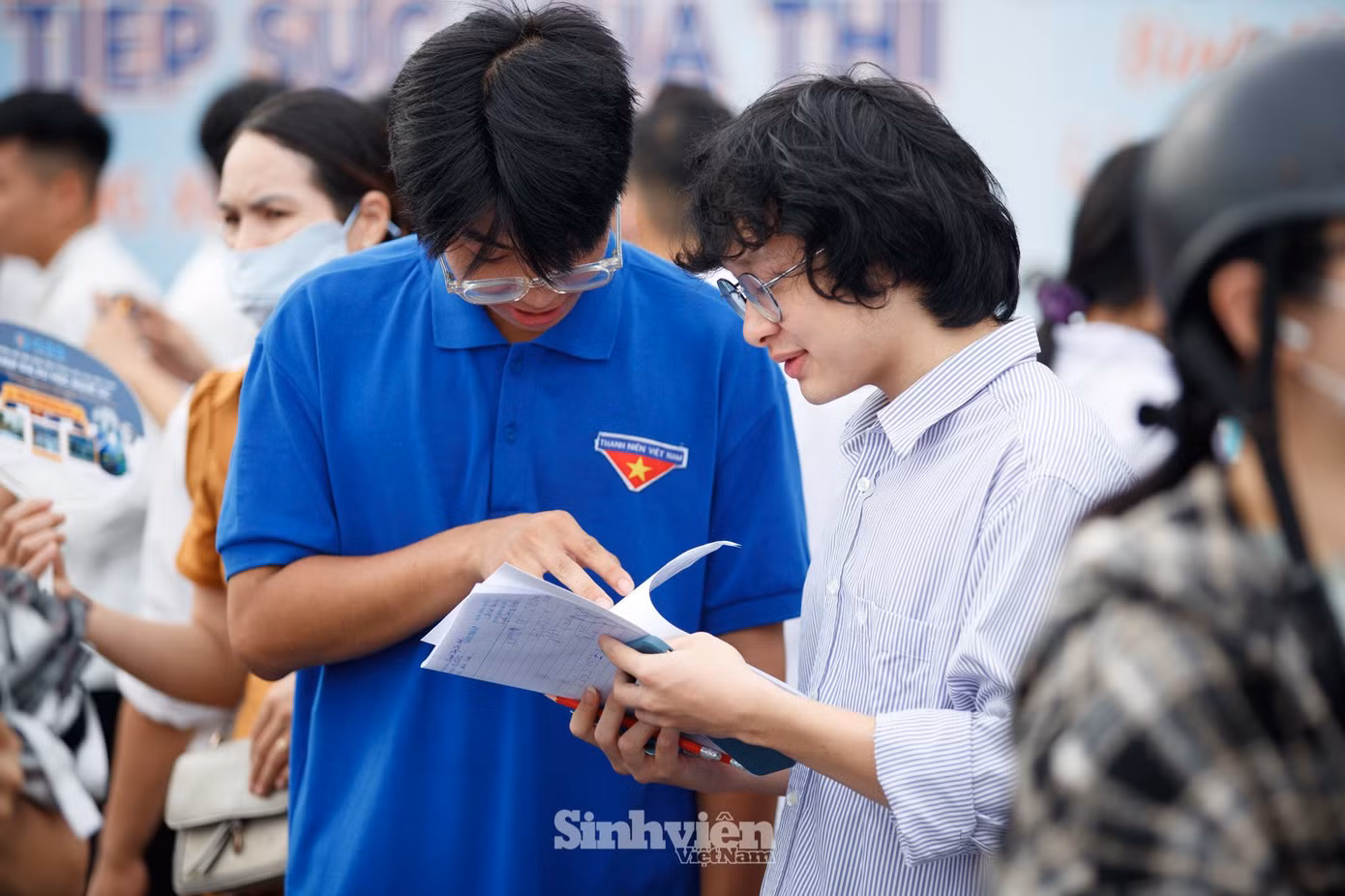 Thí sinh trao đổi bài với tình nguyện viên tại điểm thi Trường THPT Chuyên Thái Nguyên.