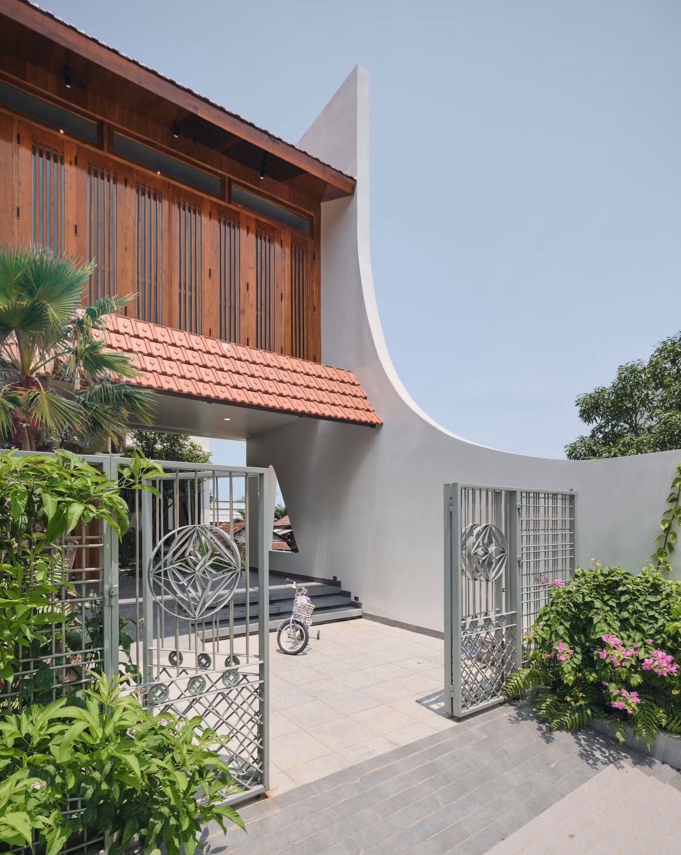 Là sự giao thoa giữa truyền thống và hiện đại, mặt tiền của ngôi nhà gây ấn tượng bởi những đường cong cách điệu mềm mại, duyên dáng. Nếp mái Á Đông cùng hệ cửa gỗ của khối nhà tầng 2 được phát triển dựa trên kiến trúc mang âm hưởng Hội An vừa hiện đại nhưng vẫn toát lên nét hoài cổ và đầy chất tự sự.