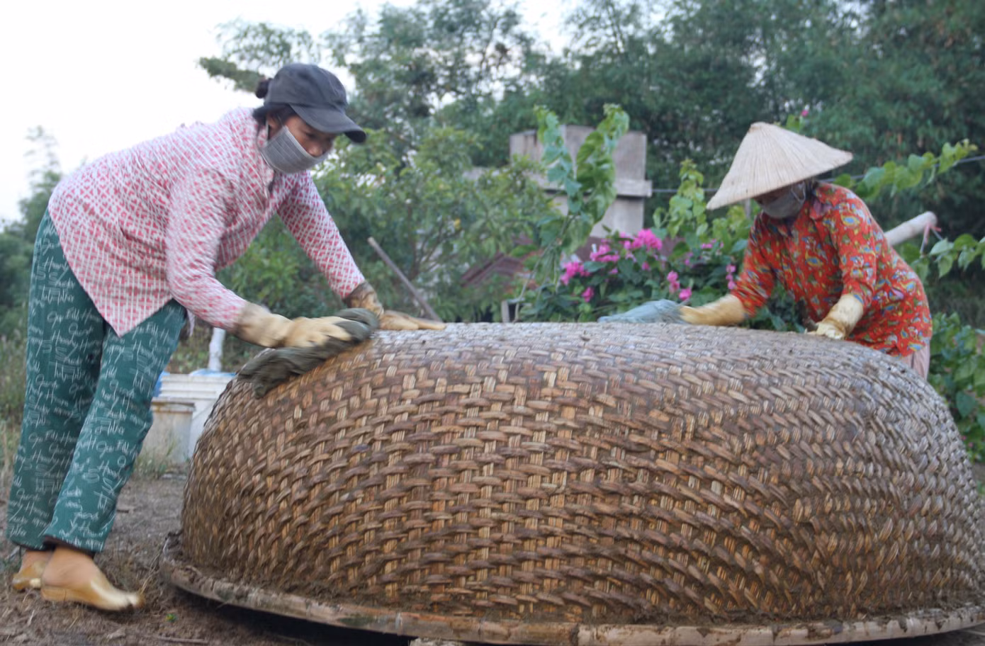 Bà Trương Thị Bích Kiều trát phân bò và nhựa dầu rái lên thúng chai để chống thấm. Ảnh: Công Hoan