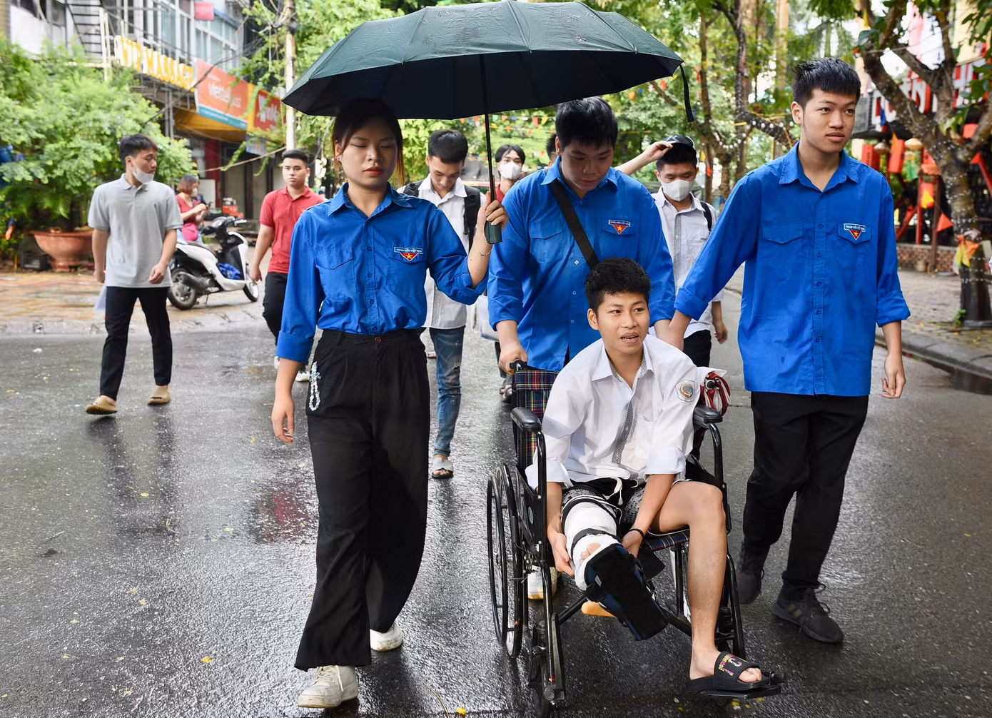 Thí sinh Nguyễn Quốc Trọng bị bó bột trước ngày thi được các tình nguyện viên hỗ trợ vào phòng thi. Ảnh: Trọng Tài