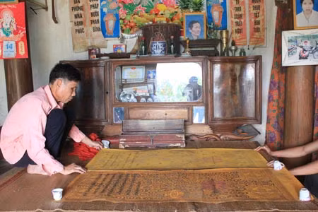 Ông Cao Văn Nguyệt cẩn trọng giở hai tấm sắc phong của vua Duy Tân