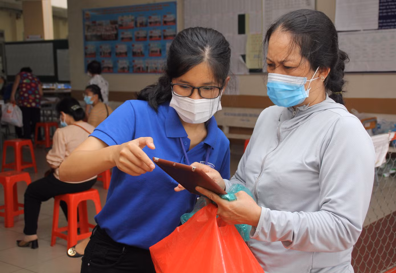 Chị Thúy hỗ trợ người dân khai báo y tế tại điểm tiêm Trường THCS Trần Quốc Toản (TP. Thủ Đức) Chị Thúy hỗ trợ người dân khai báo y tế tại điểm tiêm Trường THCS Trần Quốc Toản (TP. Thủ Đức)