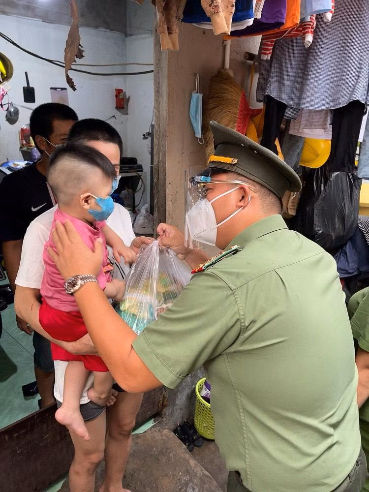 Đại úy Đặng Văn Thắng, Phó Bí thư Thường trực Đoàn Công an TPHCM gửi tặng phần quà cho một em nhỏ tại khu vực có nhiều người lao động khó khăn ở phường Tân Phong, quận 7 (Ảnh: Đoàn CATP)