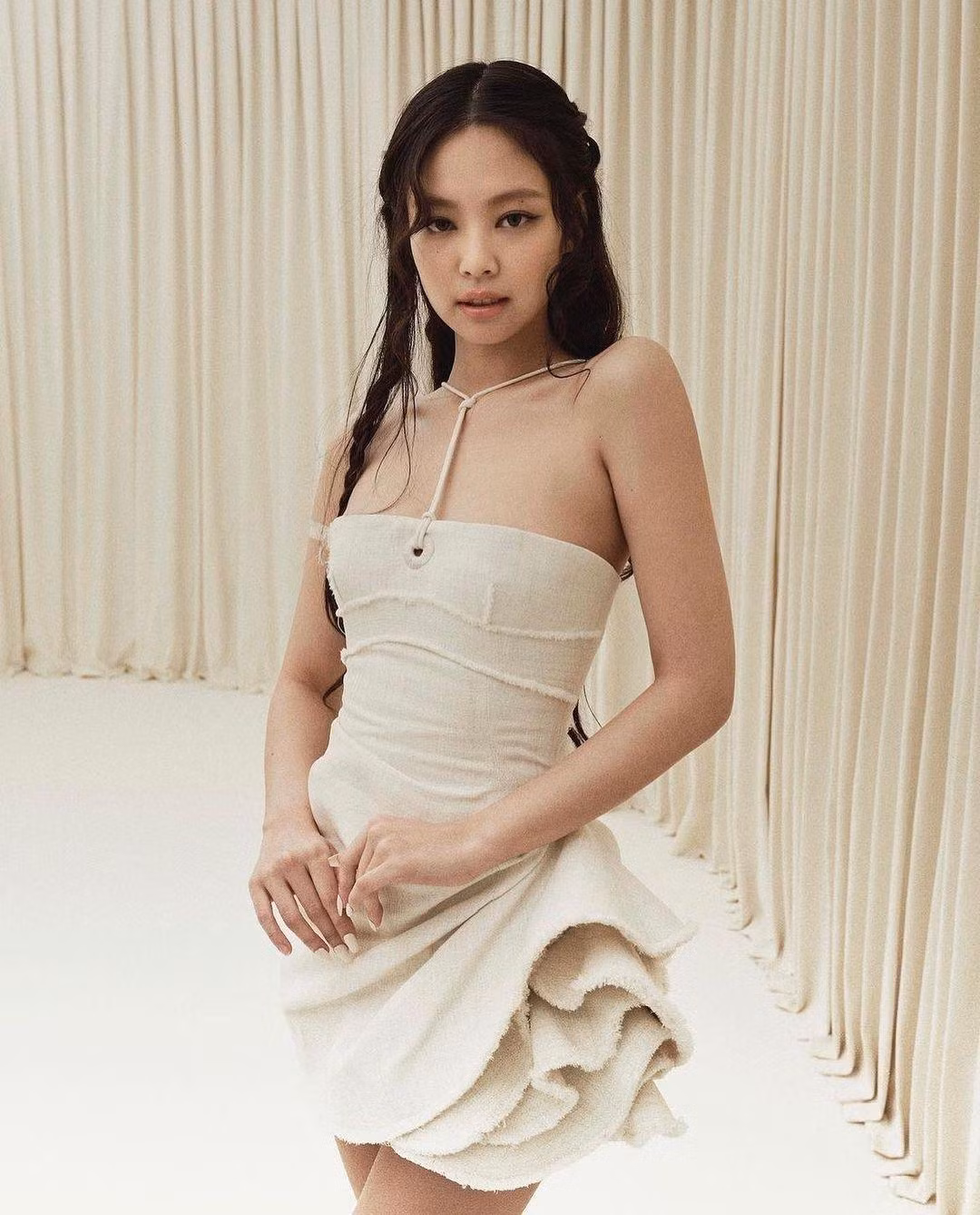 Có mặt trong show diễn, Jennie diện váy cúp ngực có thiết kế nhấn vào phần chân váy. Cô trang điểm khá đơn giản nhưng vẫn nổi bật. Thành viên BlackPink phối hợp bộ váy màu kem với chiếc túi của Jacquemus màu trắng, mang đôi sandal cùng tông màu tạo nên tổng thể nhã nhặn.
