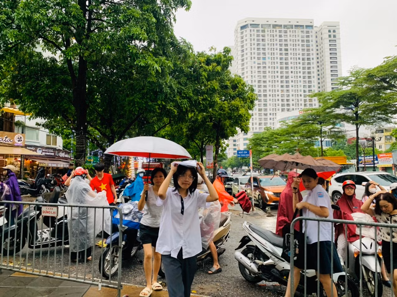 Thí sinh che mưa bước vào địa điểm thi tại THCS Yên Hòa. Ảnh: Đỗ Hợp