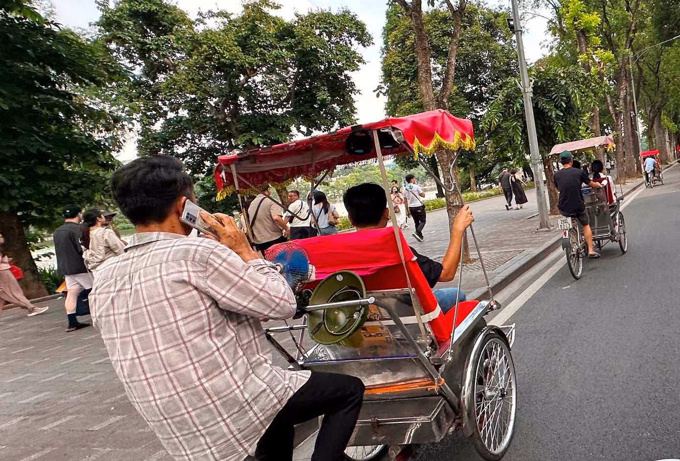 Lái xe xích lô vừa chở khách tham gia giao thông, vừa nghe điện thoại