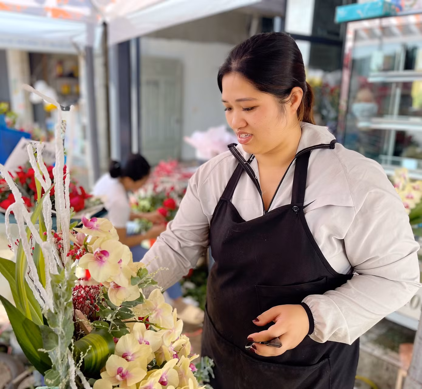Chị Nguyễn Thị Tuyết Mai cắm hoa tươi cho khách đặt tại cửa hàng