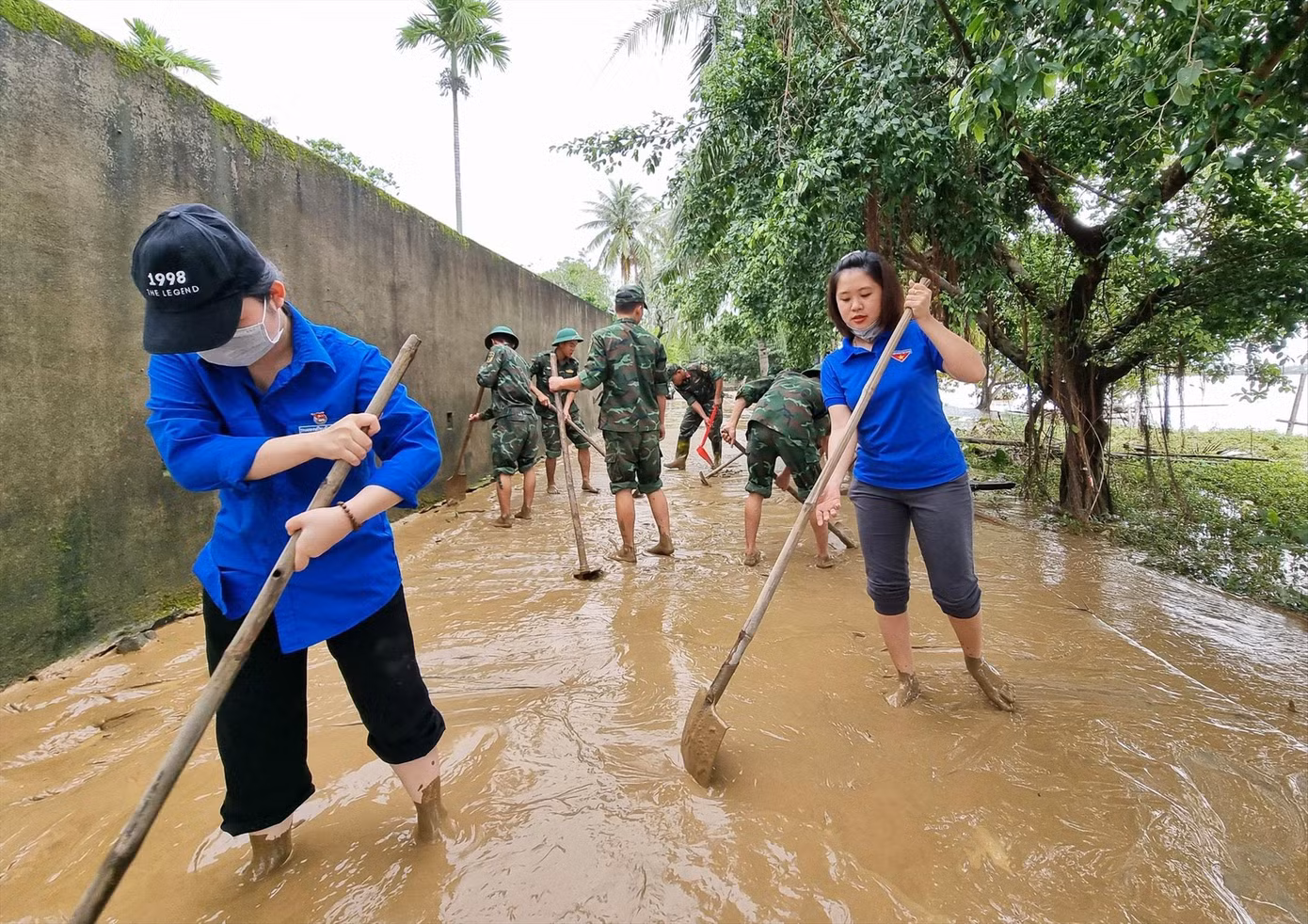 Các tình nguyện viên lội bùn giúp dân dọn đường sá, nhà cửa sau mưa lũ. Ảnh: NVCC