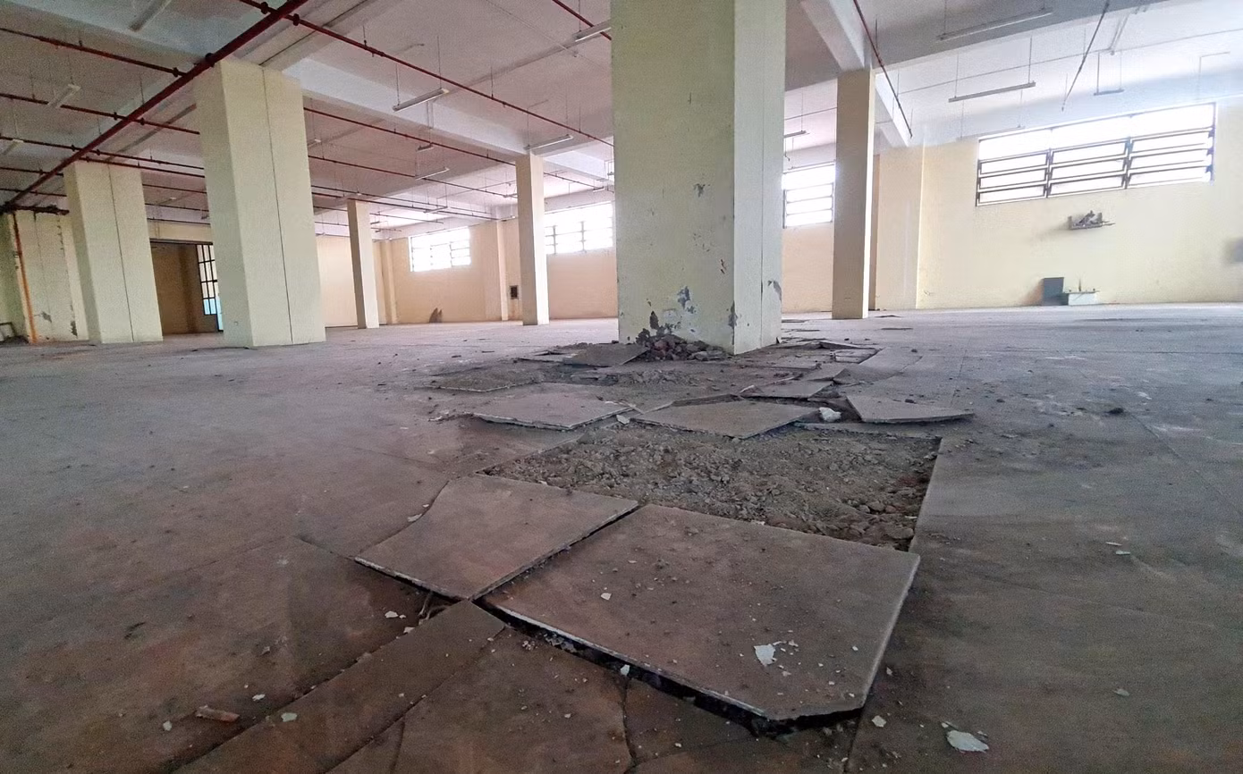 Trần nhà bị bong tróc, từng mảng sơn rơi ra ngoài. Phía dưới, nền gạch bong tróc, vỡ vụn.