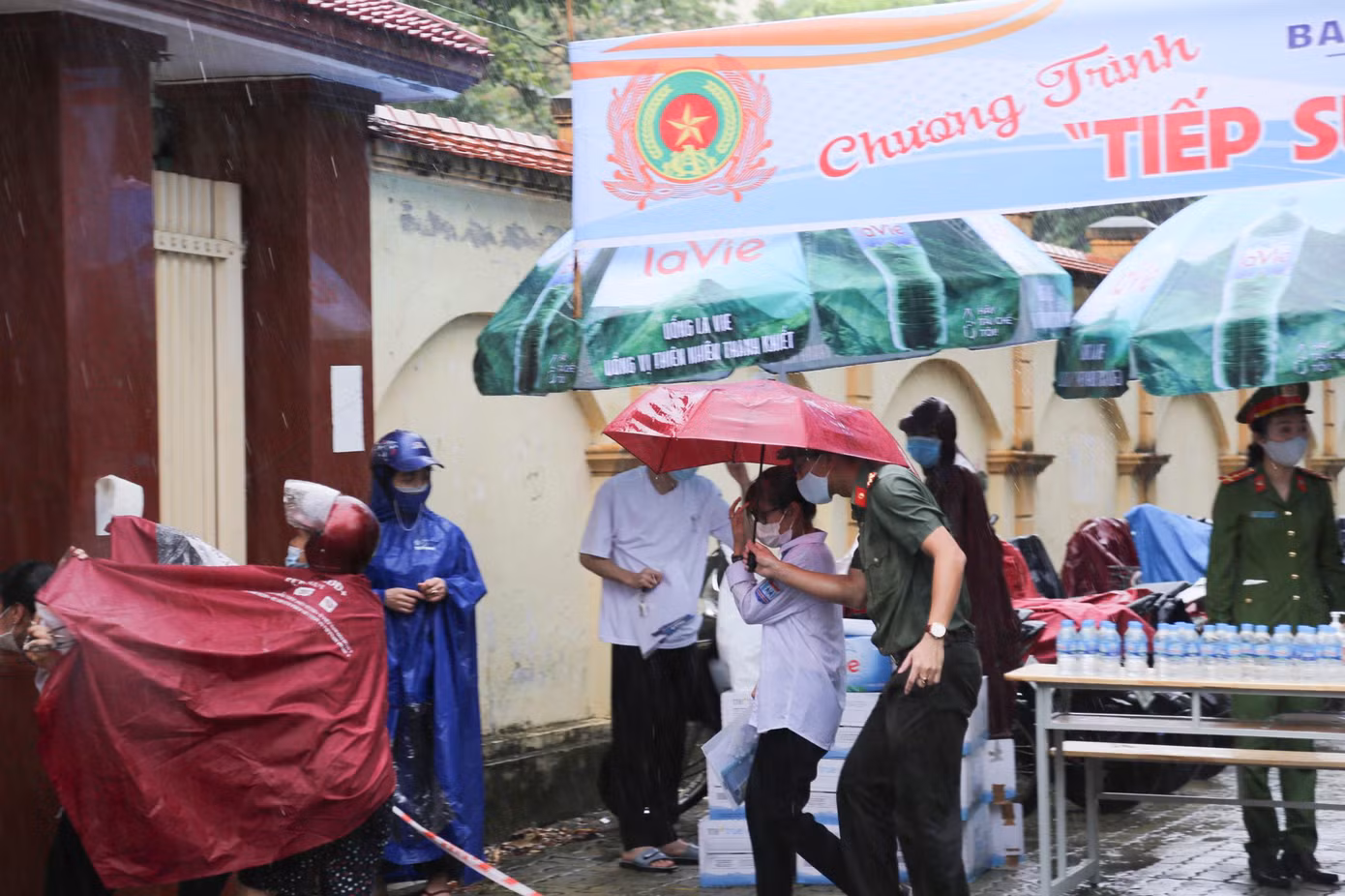 Đại úy Nguyễn Sỹ Nguyên - Phó Bí thư Đoàn Công an tỉnh Nghệ An dùng ô của mình che cho thí sinh.
