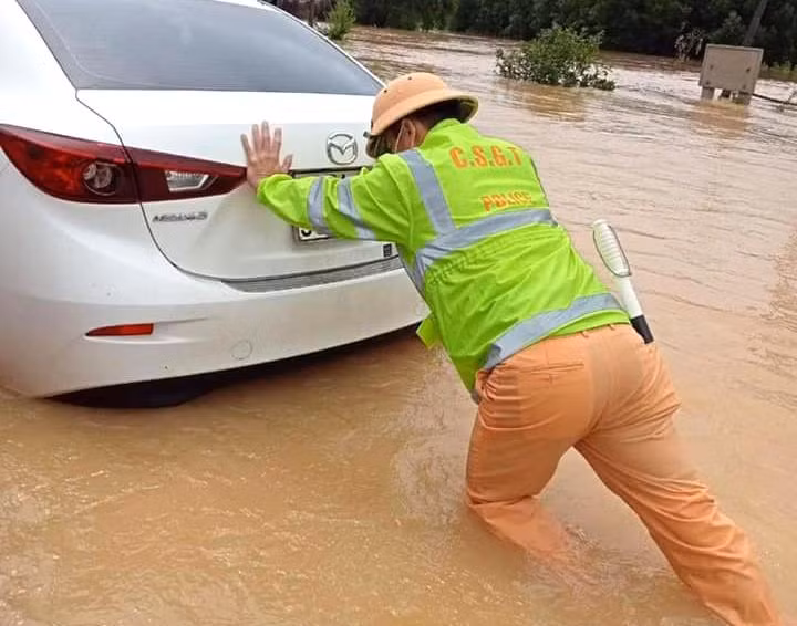 Chiến sĩ cảnh sát giao thông hỗ trợ người dân đưa xe ô tô qua đoạn đường bị ngập sâu.