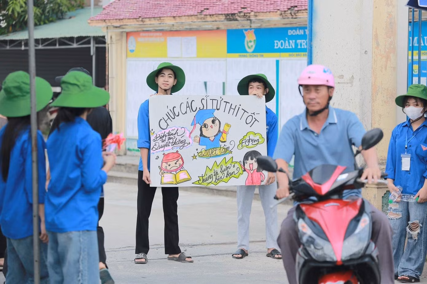 Đoàn viên trước điểm thi trường THPT Nguyễn Đức Mậu với bức tranh chúc các sĩ tử thi tốt mang lại niềm vui, động lực cho các thí sinh.
