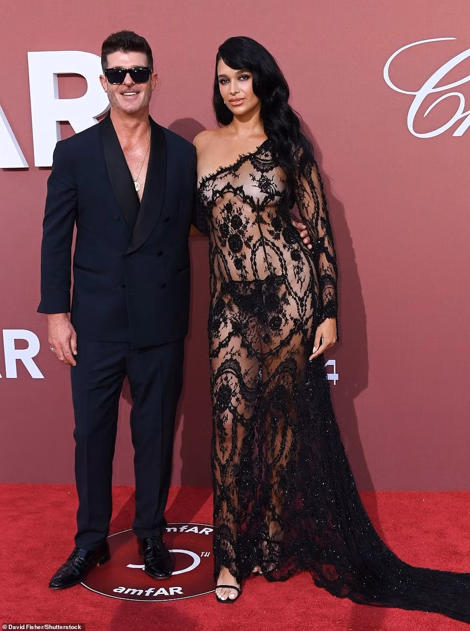 Nhạc sĩ/diễn viên Mỹ Robin Thicke sành điệu với vest đen và kính râm. Trong khi đó, bạn gái anh, người mẫu April Love Geary, khiến người nhìn "nóng mặt" với váy xuyên thấu mặc như không. Giống như Cher, cặp đôi 10 năm khoe nụ hôn nồng cháy. Ảnh: Shutterstock.