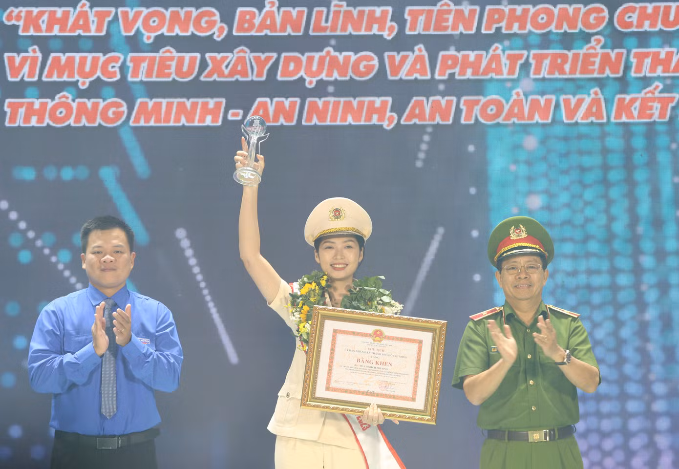 Phó Giám đốc Công an TPHCM Trần Đức Tài cùng Phó Chánh Văn phòng Trung ương Đoàn Nguyễn Hải Nam tuyên dương Đại úy Võ Thị Bích Phương.