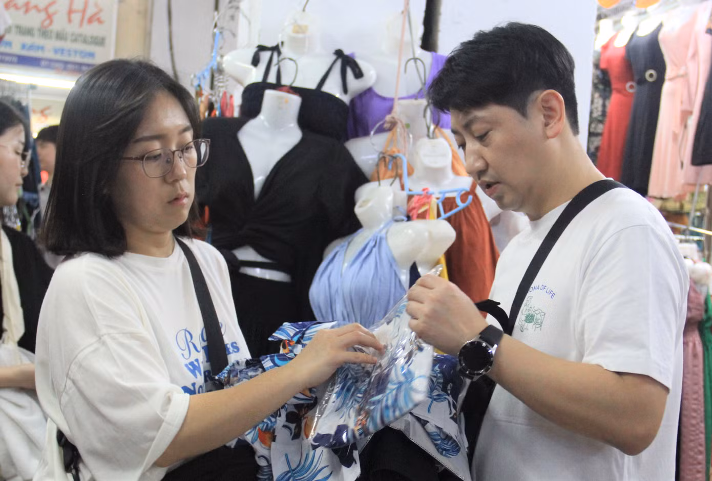 Hai du khách Hàn Quốc xem áo quần. Các loại áo chất liệu vải mát, nhẹ rất được du khách ưa chuộng vì thuận tiện đi biển hay vui chơi ngoài trời.