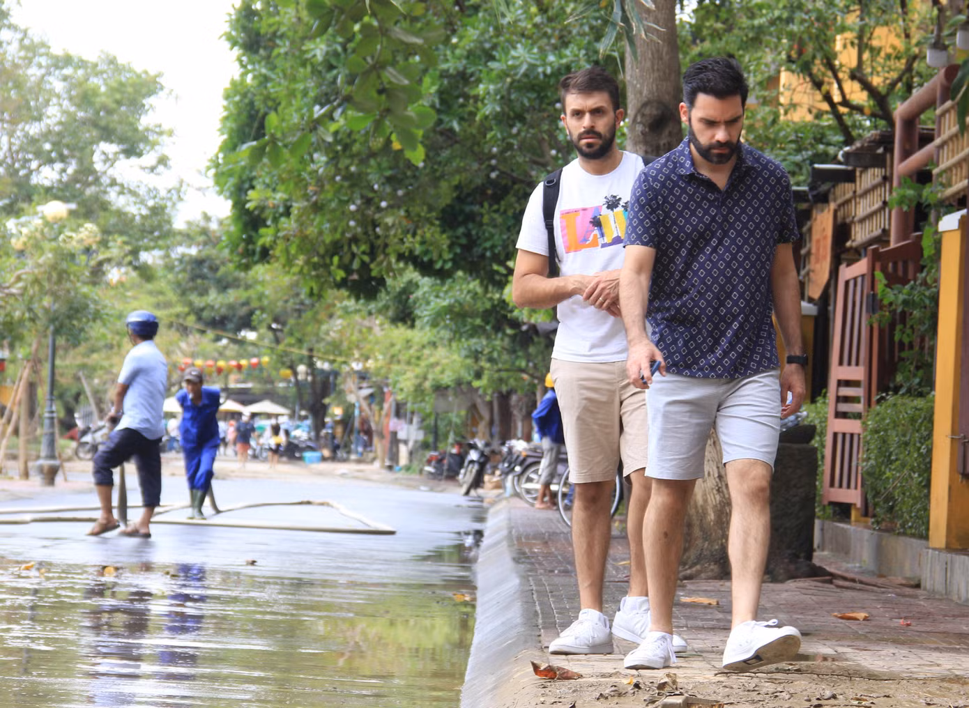 Du khách "né" đoạn đường còn đầy bùn bẩn sau khi nước rút. Hiện một số đoạn đường ven sông nước vẫn còn ở mắt cá chân.