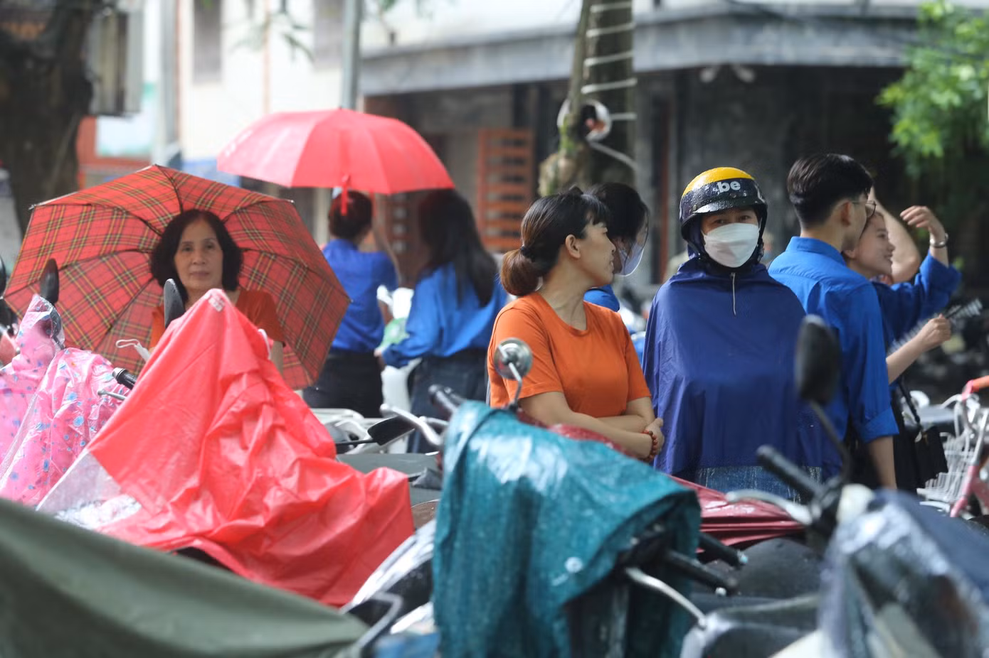 Phụ huynh đội mưa chờ thí sinh ngoài cổng trường.