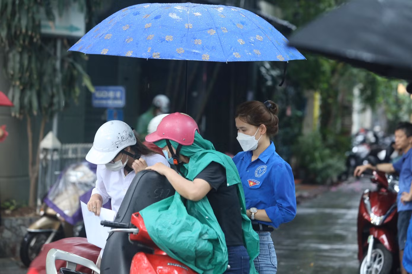 Các tình nguyện viên đến tận xe để che ô cho học sinh và phụ huynh.