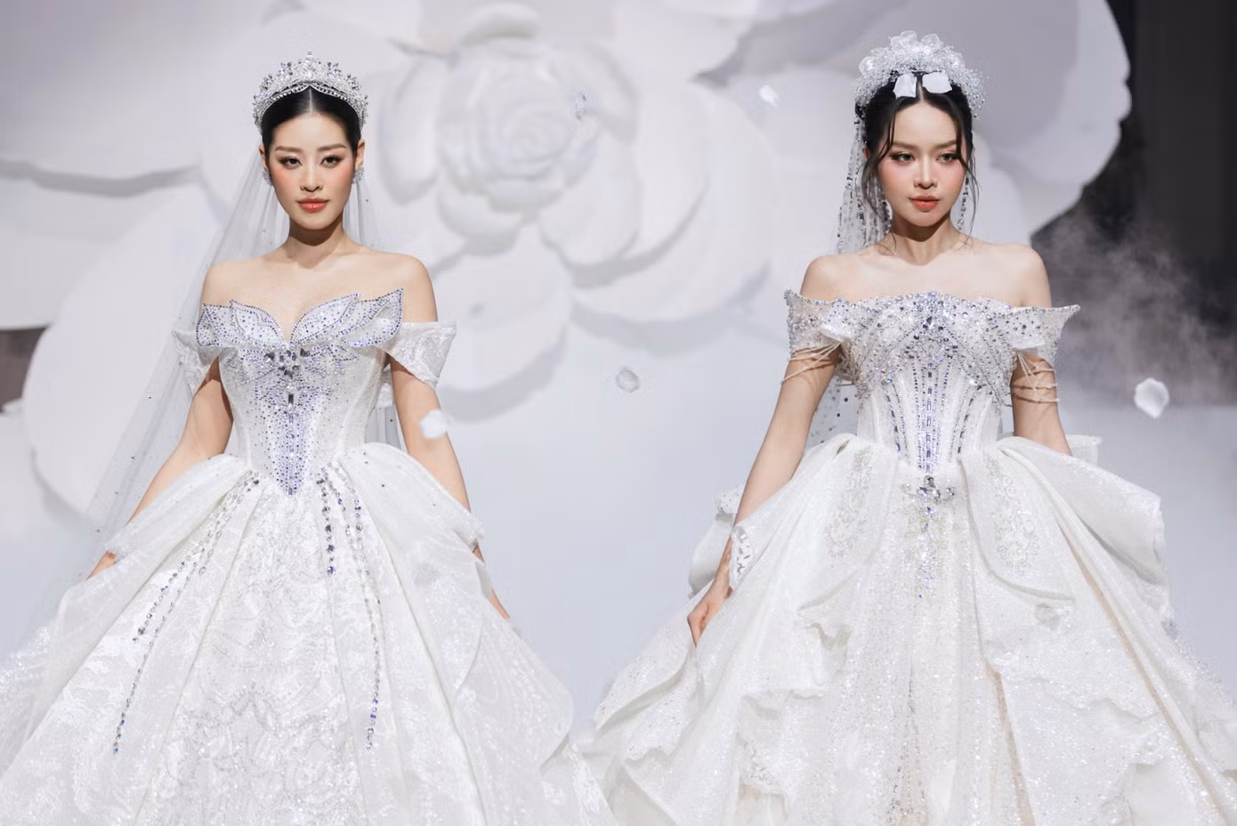 Cả hai người đẹp trình diễn trong thiết kế váy xòe trễ vai với chất liệu bắt sáng và chi tiết kim sa nổi bật. Phụ kiện như vương miện cô dâu và khăn voan đính đá Swarovski giúp hoàn thiện hình ảnh lộng lẫy, gợi liên tưởng đến những nàng công chúa cổ tích.