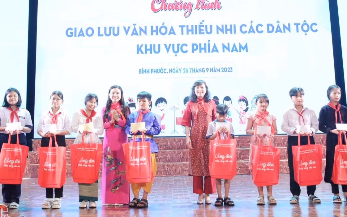 Bí thư Trung ương Đoàn, Chủ tịch Hội đồng Đội Trung ương Nguyễn Phạm Duy Trang (thứ tư từ trái sang) và Phó Bí thư Thường trực Tỉnh ủy, Chủ tịch HĐND tỉnh Bình Phước Huỳnh Thị Hằng (thứ năm từ phải sang) tặng quà cho thiếu nhi