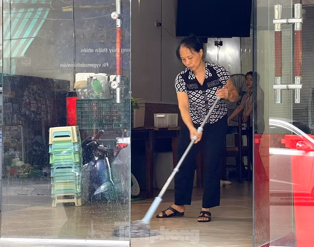 Một nhân viên trên phố Đường Thành lau dọn cửa hàng chờ đến ngày được bán hàng trở lại
