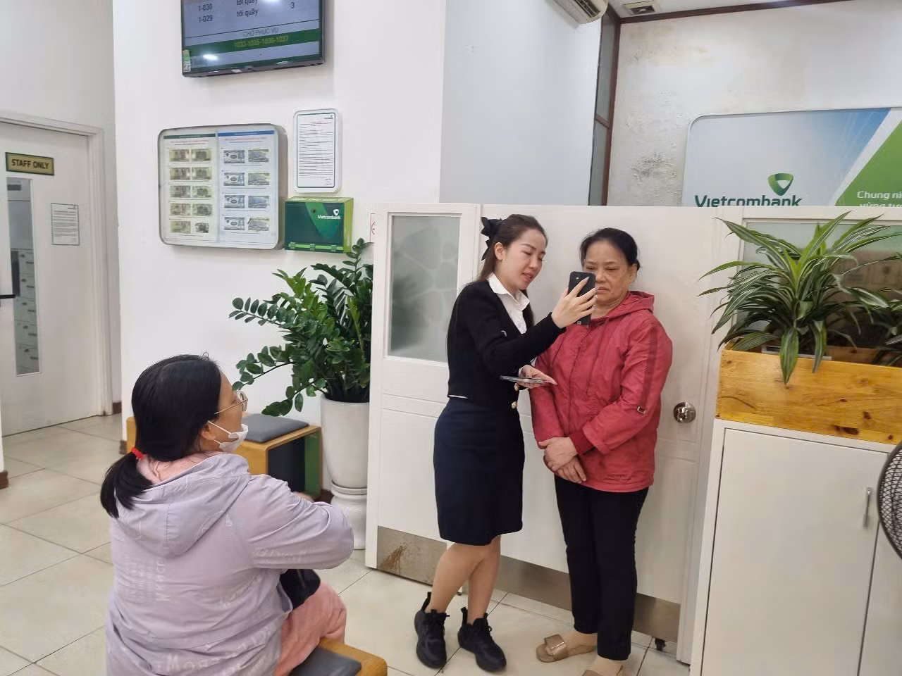 Nhân viên ngân hàng Vietcombank cài đặt cho khách hàng sinh trắc học (ảnh: N.M).