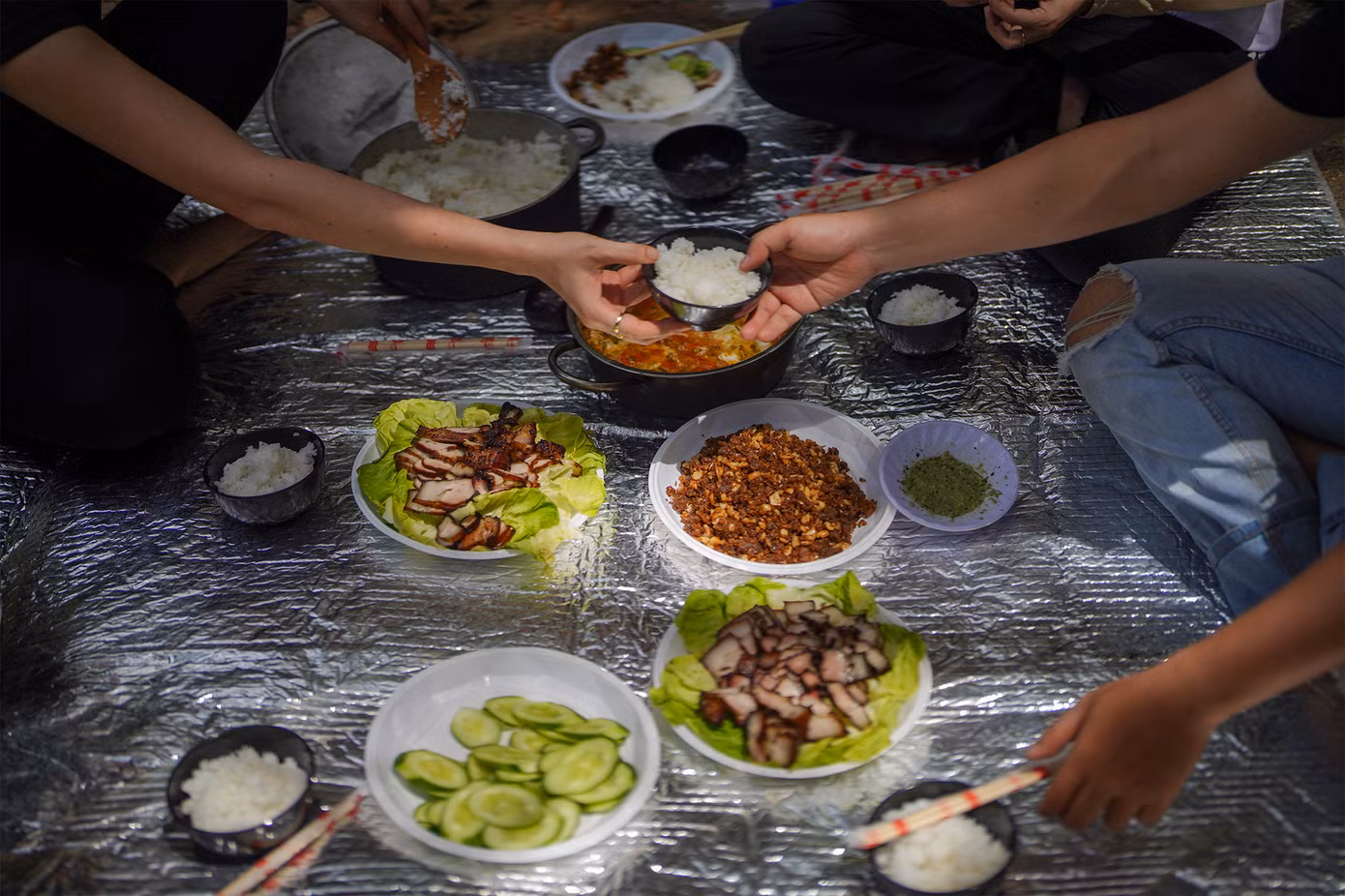 Trong khi du khách đi bộ thì đội hỗ trợ đã chuẩn bị cơm trưa. Nhóm khách trong ảnh được phục vụ món thịt lợn xông khói nướng hạt dỗi khá độc đáo của địa phương. Dòng nước suối nơi cấm trại mát lạnh đến nỗi có thể ngâm cả chai nước ngọt, đợi tầm 15 phút là có thể thưởng thức.