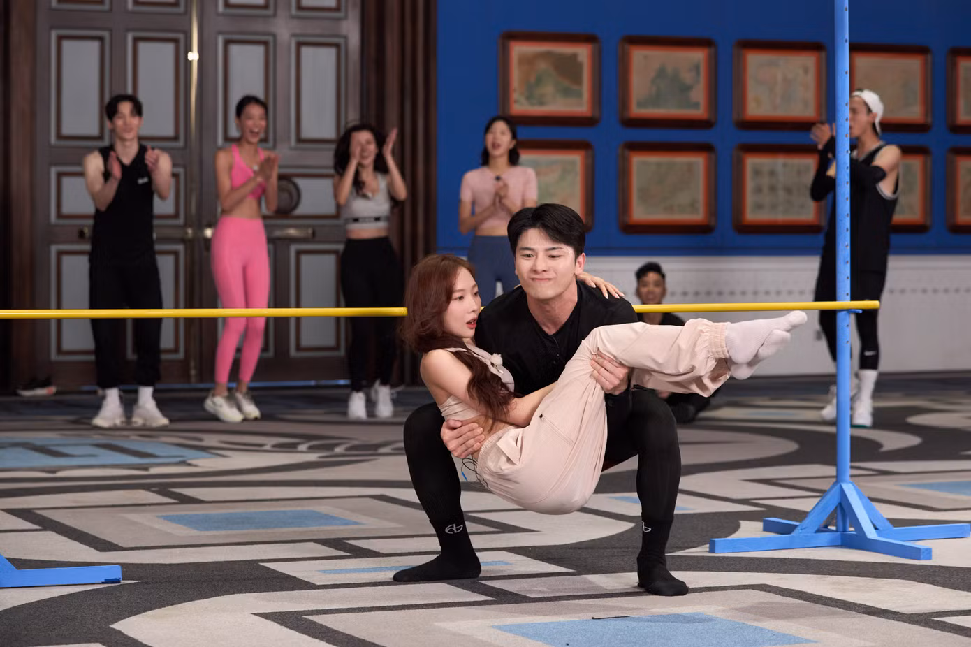 Các người chơi thực hiện thử thách vượt sào, ăn mì, vừa bồng bế người chơi nữ vừa squat...
