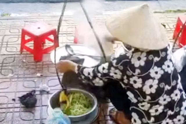 Bà H.T.T có hành vi đổ thức ăn thừa vào nồi nước lèo. Ảnh cắt từ clip.