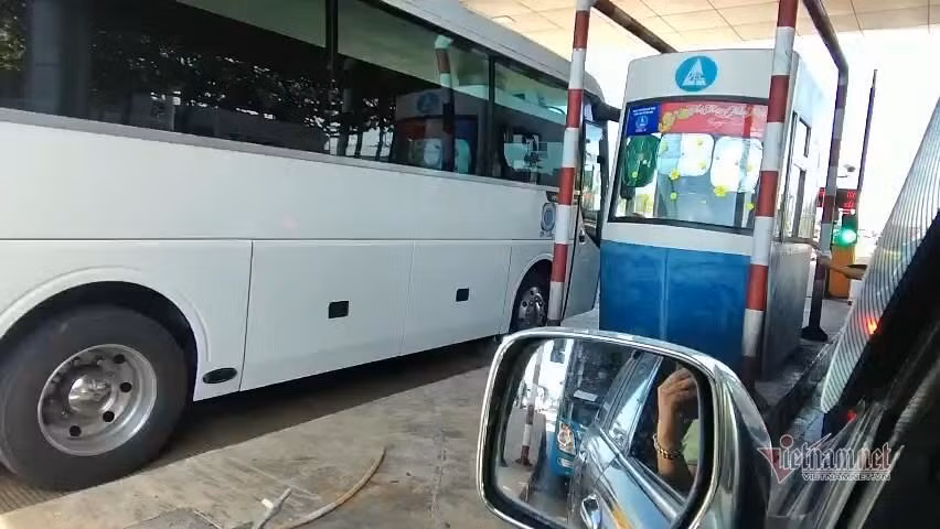 Nhân viên trạm thu phí tiến hành thu phí thủ công, bất chấp xe cộ đang ùn tắc kéo dài