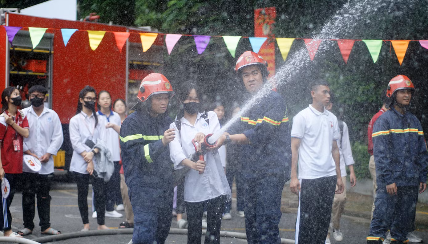 Cán bộ, chiến sĩ PCCC&amp;CNCH hướng dẫn học sinh, sinh viên cách phun vòi nước chữa cháy hiệu quả.