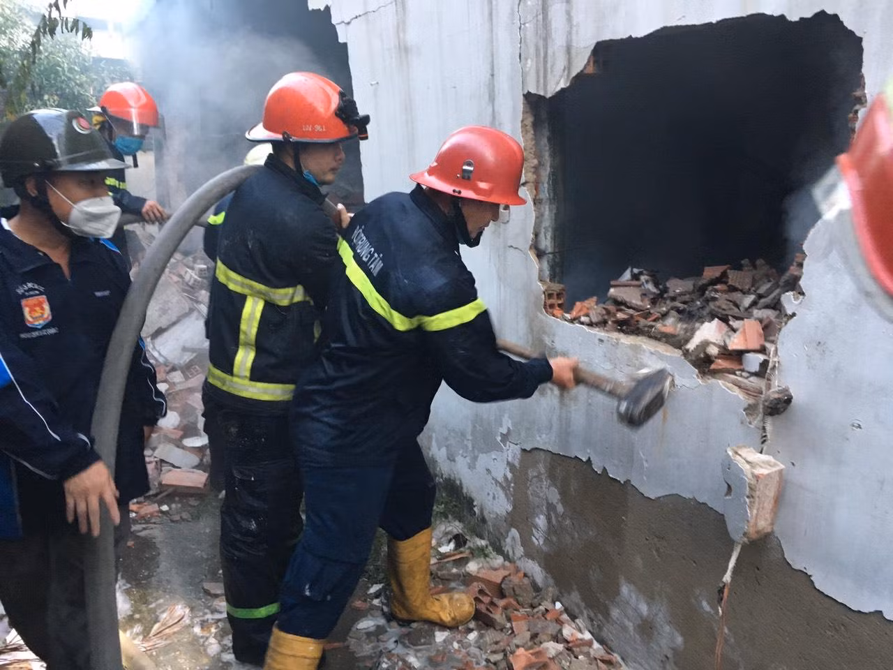 Lực lượng chức năng đập tường tiếp cận hiện trường dập lửa.