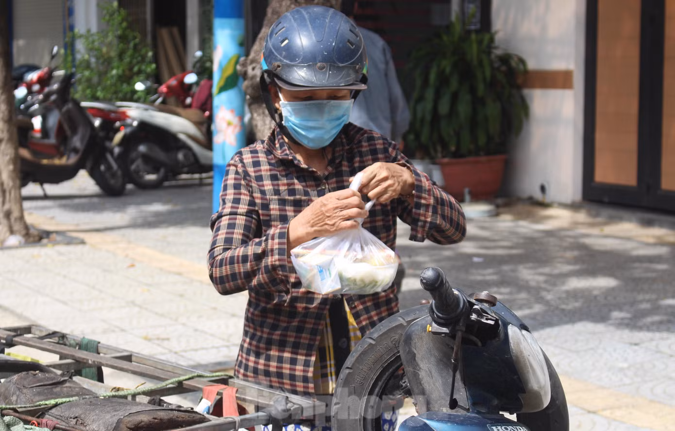Nhận phần ăn trưa, chị Lê Thị Tuyết (54 tuổi, quê Quảng Ngãi) cẩn thận treo vào xe máy. "Một mình tui nuôi 2 đứa con còn đang tuổi ăn tuổi học nên đỡ được đồng nào hay đồng đó. Phần mì này tui để lát nữa mới ăn, chứ ăn sớm chiều lại đói", chị Tuyết nói rồi nổ xe máy rồi tiếp tục rong ruổi khắp các con phố để mua ve chai. Nhận phần ăn trưa, chị Lê Thị Tuyết (54 tuổi, quê Quảng Ngãi) cẩn thận treo vào xe máy. "Một mình tui nuôi 2 đứa con còn đang tuổi ăn tuổi học nên đỡ được đồng nào hay đồng đó. Phần mì này tui để lát nữa mới ăn, chứ ăn sớm chiều lại đói", chị Tuyết nói rồi nổ xe máy rồi tiếp tục rong ruổi khắp các con phố để mua ve chai.