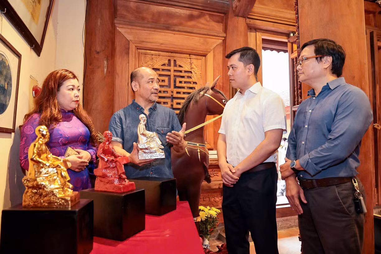Hoạ sĩ Vũ Xuân Đông giới thiệu về tác phẩm “Bác Hồ ngồi đọc báo Nhân Dân” với các đại biểu.