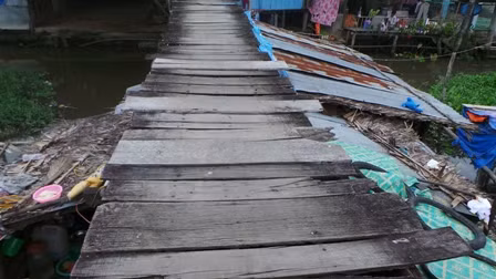 Mặt cầu bằng ván gỗ tạp, nhiều chỗ đã bị mục, tuột đinh, chông chênh như thế này