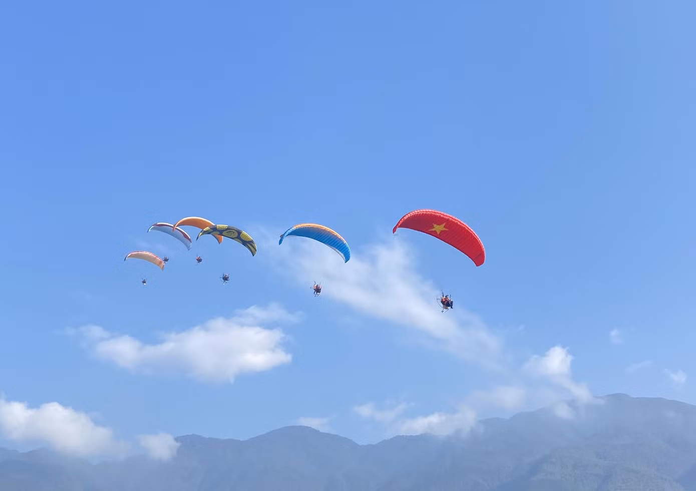 Các vận động viên trình diễn bay dù lượn và du khách trải nghiệm bay cùng phi công trên bầu trời.