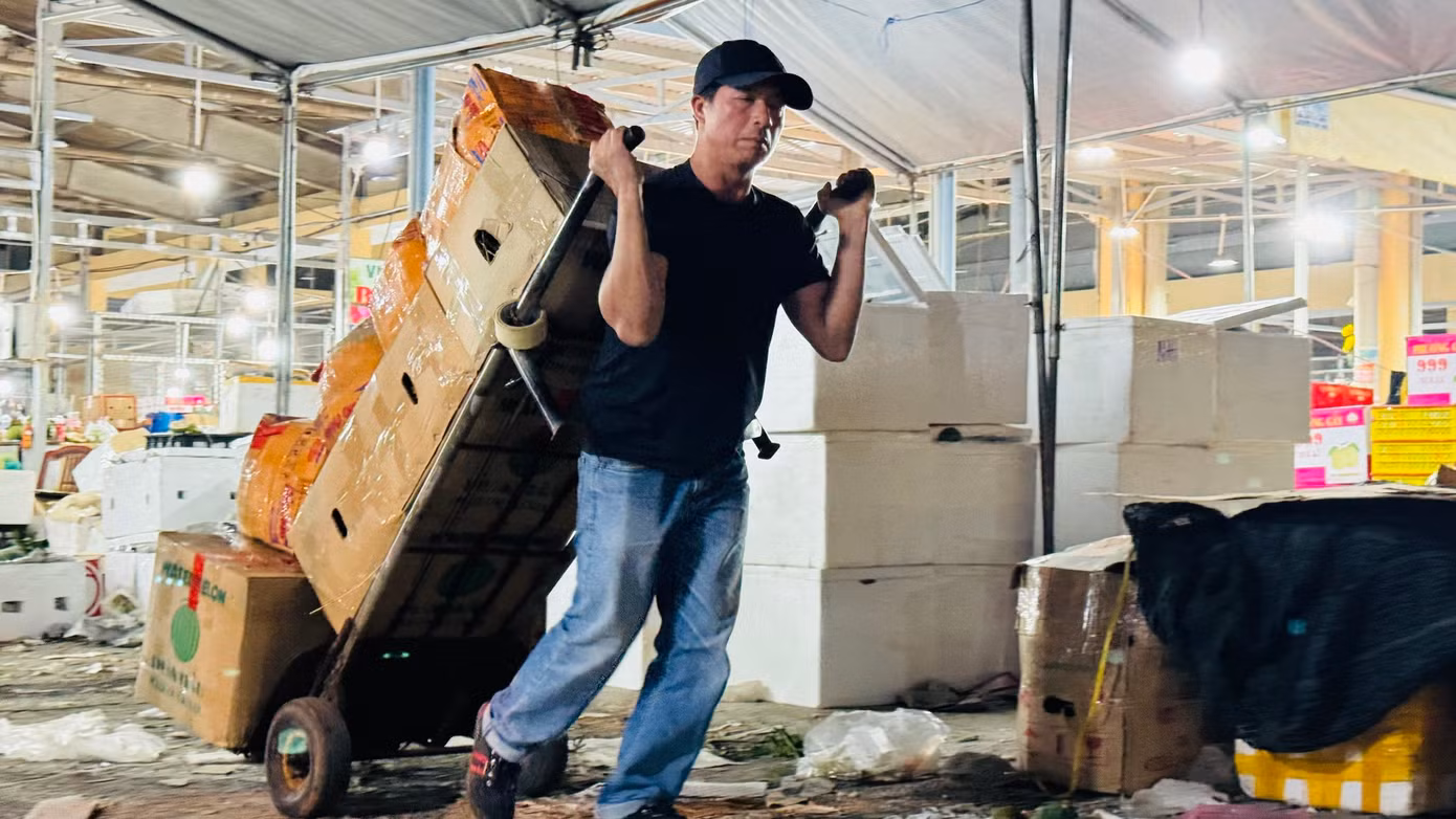 “Mỗi thùng hàng kéo từ xe vào quầy của tiểu thương được trả công 2.000 đồng. Một chuyến thường chất 10 thùng. Mỗi người thường kéo 300 - 400 thùng trong đêm, kiếm khoảng 800.000 đồng. Dịp Tết, dù công việc vất vả, kéo dài nhưng với mong muốn kiếm thêm thu nhập để trang trải cho cái Tết nên mệt mấy cũng phải làm”, anh Anh thổ lộ. Ảnh: Nguyễn Ngọc