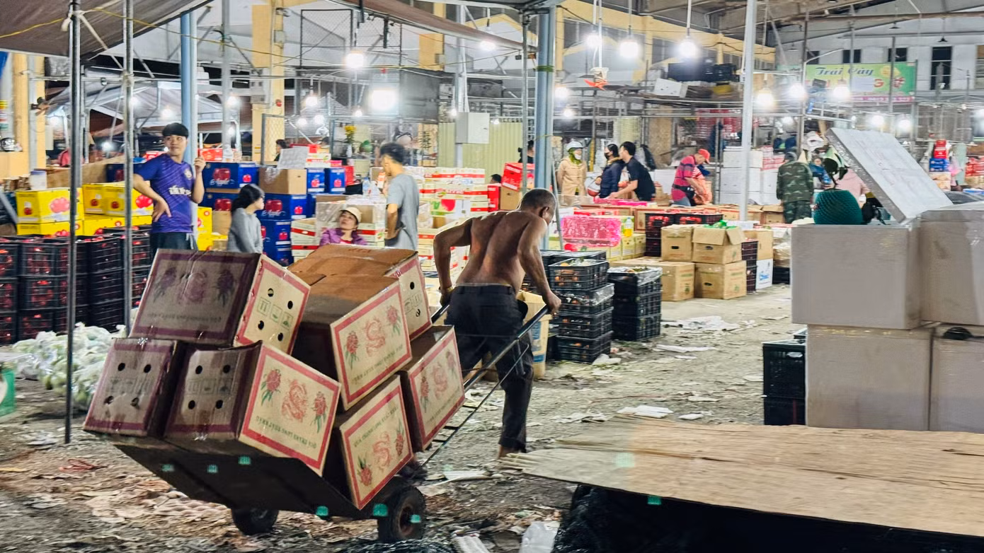 Họ bốc vác, vận chuyển cả trăm tấn hàng đi đến các ki-ốt trong chợ và đưa lên các xe tải nhỏ mang đi khắp nơi trong và ngoài tỉnh phục vụ nhu cầu mua sắm Tết của người dân. Ảnh: Nguyễn Ngọc