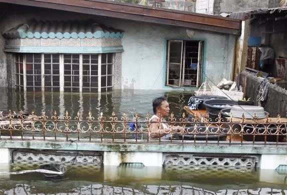 Một người dân vận chuyển đồ đạc trong cảnh nước ngập ngang ngực trước nhà mình ở thị xã Dampalit, thành phố Malabon, phía bắc Manila