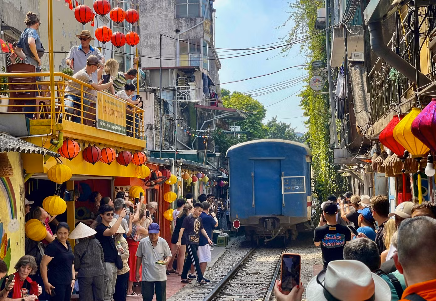 Khoảnh khắc đoàn tàu chạy qua khu phố, du khách đứng lô nhô hai bên đường tàu để quay phim, chụp hình.